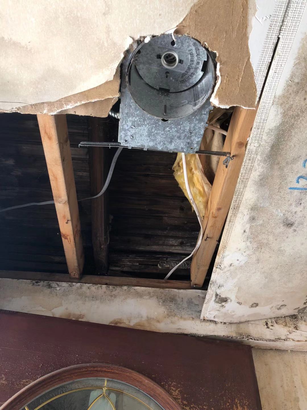 Old metal ceiling junction box exposed in torn lath and plaster, with old wiring running through wood joists above.