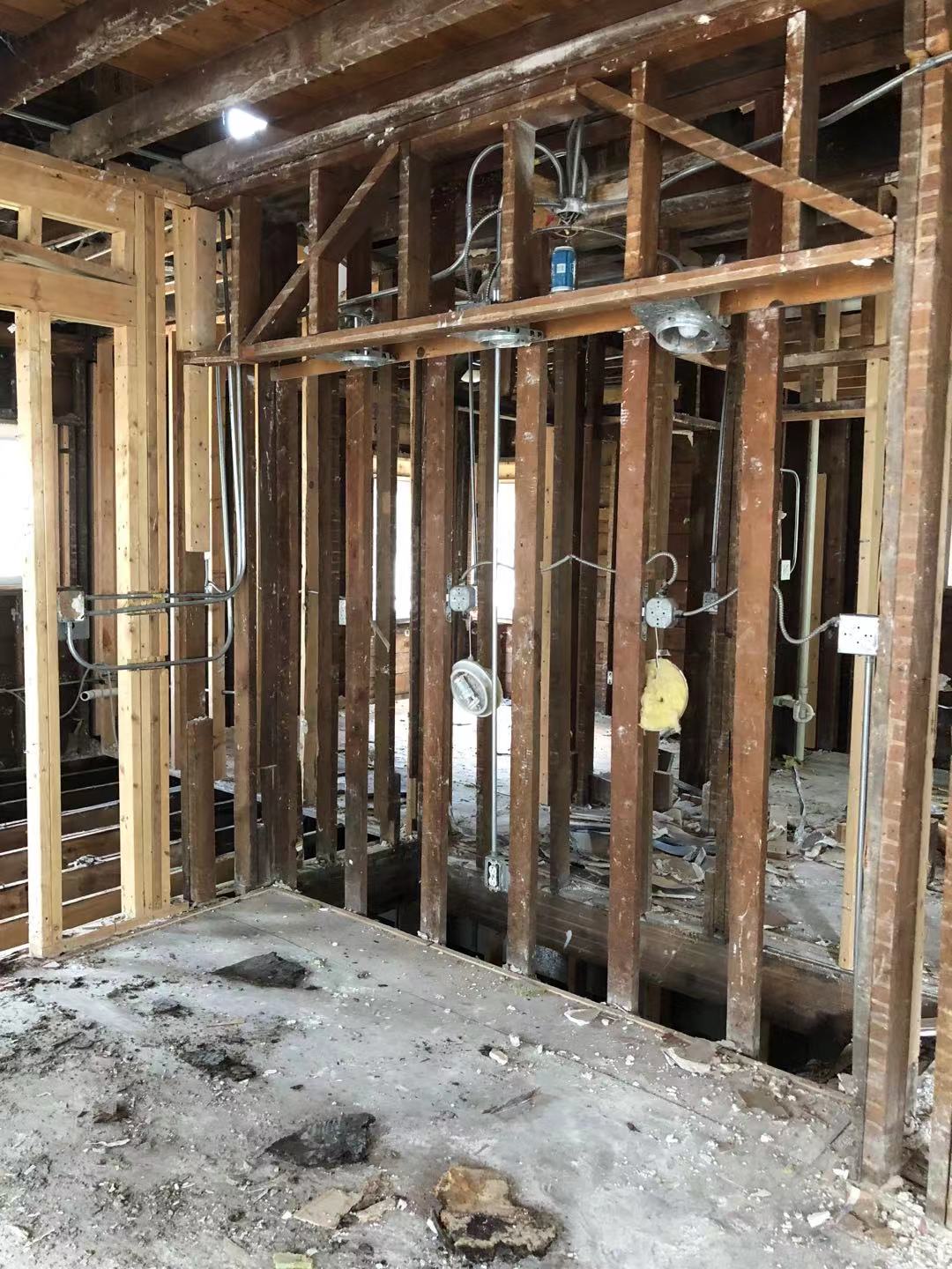 Open framing with multiple old electrical boxes and conduit visible — pre-redo state, the original wiring that had to be replaced.