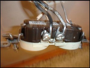 Older solid aluminum branch wiring landed on the screw terminals of a receptacle. The wire is dull silver-gray and single-conductor.